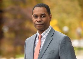 Headshot, outdoors wearing a grey suit and tie.