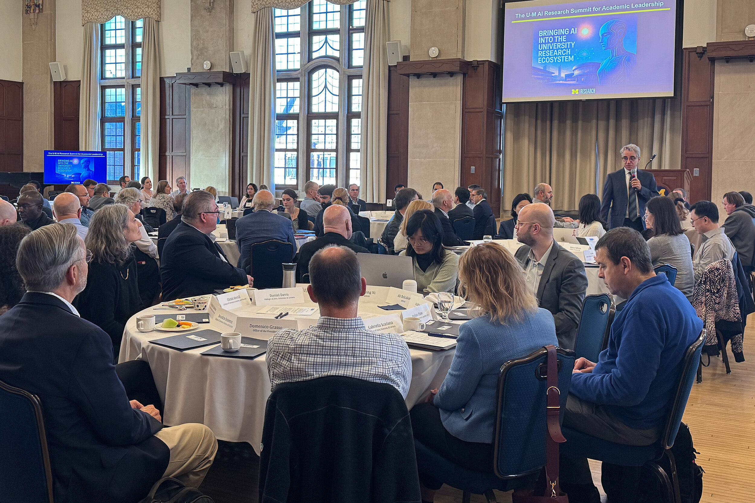 A group listens to the Vice President for Research lead discussions about AI at a leadership summit.